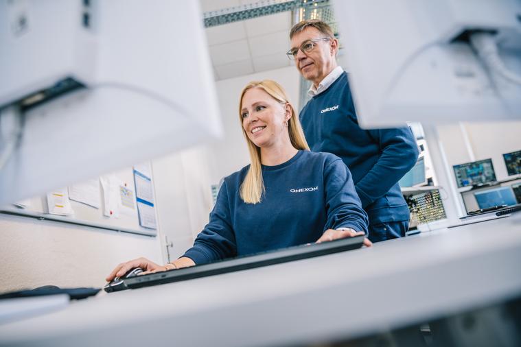 Zwei Kollegen, die vor einen Bildschirm sitzen bzw. stehen