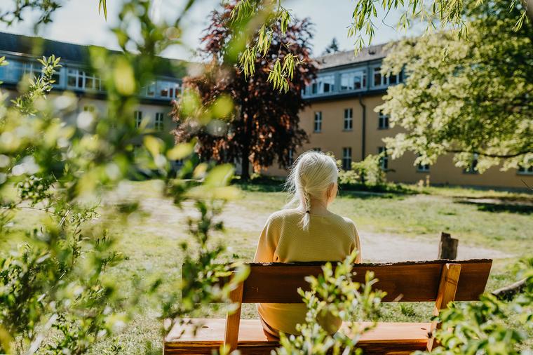 Bewohnerin blickt auf einen grünen Innenhof