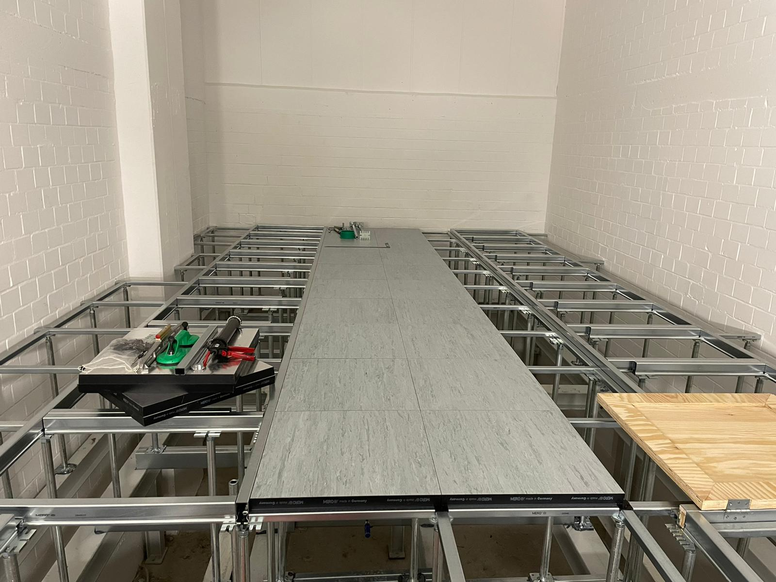 Schaltwartenboden mit zum Teil verlegten Doppelbodenplatten und Luke